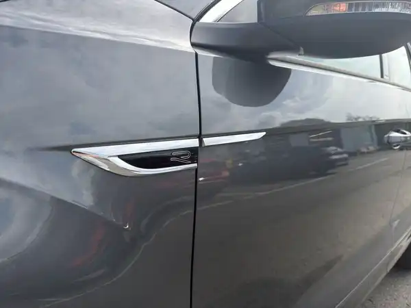 Das Bild zeigt die Seite eines grauen VW T-Roc. Es handelt sich um eine Aufnahme des Fahrzeuges von der Seite.