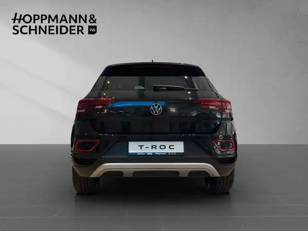 Das Bild zeigt die Rückansicht eines schwarzen VW T-Roc. Im oberen Bereich ist das Händlerlogo 'HOPPMANN & SCHNEIDER' eingeblendet.