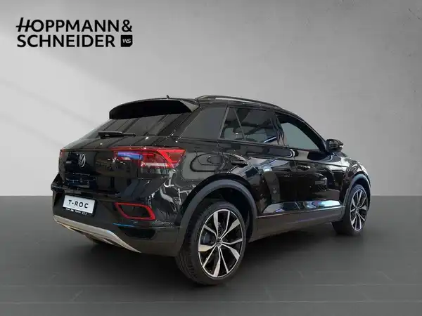 Das Bild zeigt einen schwarzen VW T-Roc von hinten. Das Händlersymbol "HOPPMANN & SCHNEIDER" ist im oberen Bereich des Bildes sichtbar.