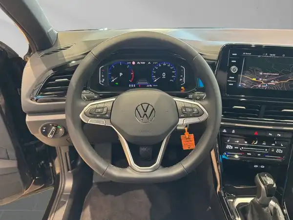 Das Bild zeigt das Innere eines Volkswagen T-ROC mit einem schwarzen Interieur. Die Aufnahme ist von der Fahrerseite aus gemacht.
