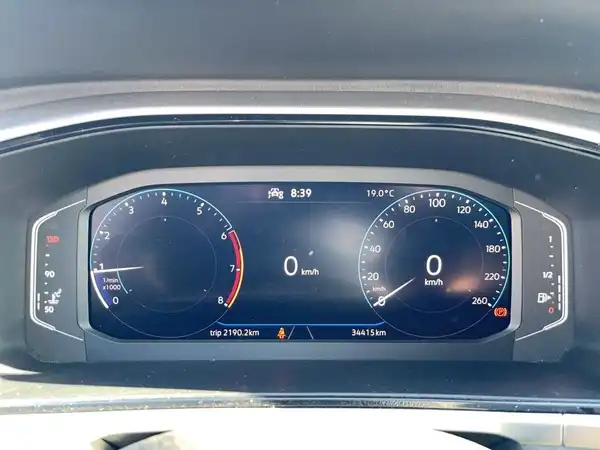 Das Bild zeigt das Armaturenbrett eines VW T-ROC mit einem digitalen Dashboard. Die Anzeige zeigt mehrere Instrumente, darunter Geschwindigkeitsmesser und Kilometerzähler.