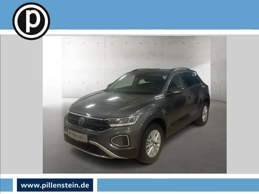 Das Bild zeigt ein graues Fahrzeug (VW T-ROC) aus der Seitenansicht. Das Händlerlogo ist vorhanden und es gibt markante Texteinblendungen.