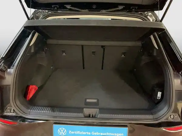 Das Bild zeigt den Kofferraum eines schwarzen VW T-ROC. Es enthält das Händlerlogo und markante Texteinblendungen.