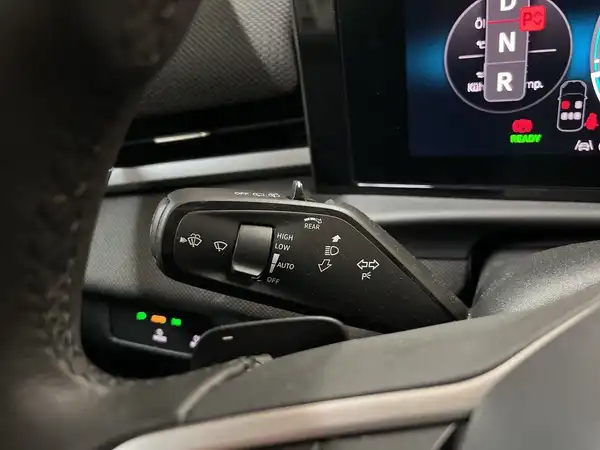 Das Bild zeigt den Innenraum eines Fahrzeugs, speziell einen Ausschnitt des Armaturenbretts mit Schaltern und digitalen Anzeigen. Die Interieurfarbe ist schwarz.