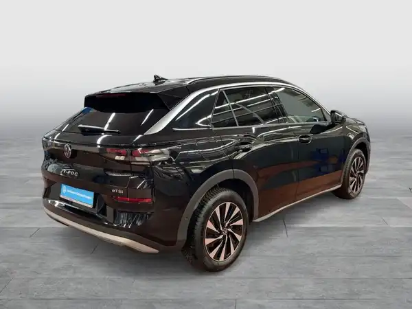 Das Bild zeigt einen schwarzen VW T-ROC aus einer Rückansicht, aufgenommen in einem neutralen Umfeld.