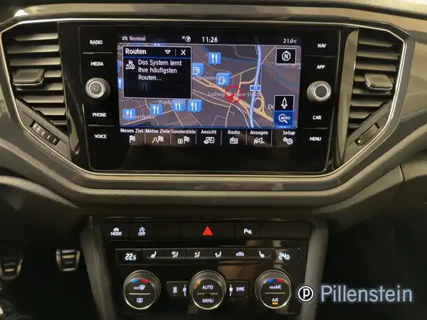 Aufnahme des Innenraums eines VW T-ROC mit schwarzem Interieur, einschließlich Navigationssystem und Händlerlogo.