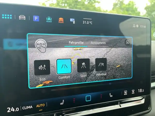 Das Bild zeigt das Innere eines VW T-ROC mit einem Infotainment-Bildschirm, der verschiedene Betriebsprofile anzeigt.