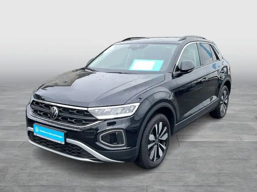 Das Bild zeigt einen schwarzen VW T-ROC aus der Frontansicht. Es sind markante Texteinblendungen auf dem Foto vorhanden.