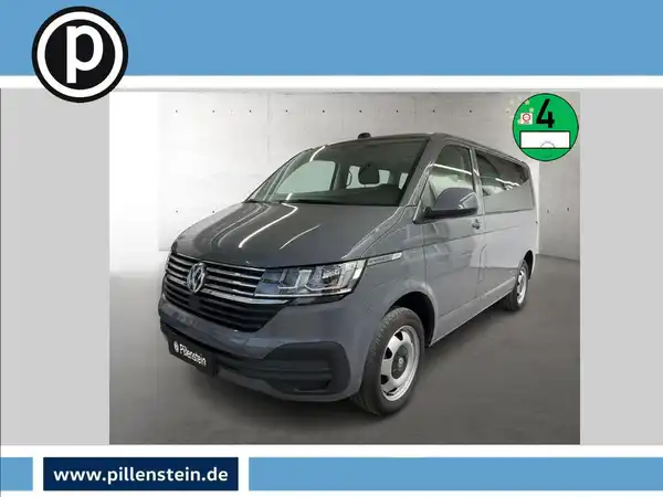 Das Bild zeigt einen grauen VW T6.1 CARAVELLE aus der Frontansicht. Das Händlerlogo ist auf dem Bild eingeblendet und es enthält zusätzlich markante Texteinblendungen.