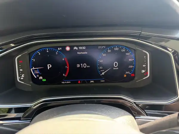 Das Bild zeigt das Armaturenbrett eines VW TAIGO STYLE, mit einem digitalen Display, das Geschwindigkeits- und Fahrstatusanzeigen zeigt. Es handelt sich um eine Innenaufnahme in schwarzer Farbe.