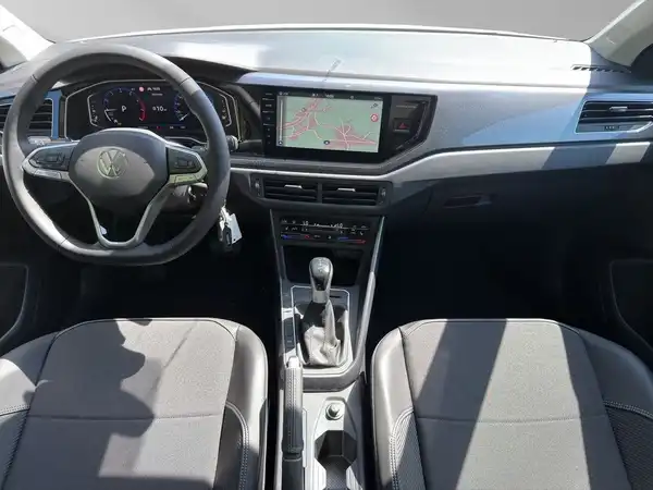 Das Bild zeigt das Innere eines VW TAIGO mit grauen Sitzbezügen und einem Navigationsbildschirm. Es enthält zudem markante Texteinblendungen.