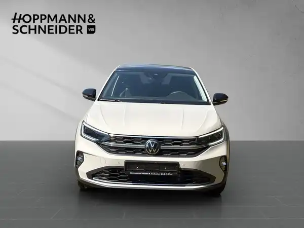 Ein Bild eines beige VW TAIGO STYLE, aufgenommen von vorne, mit dem Händlerlogo HOPPMANN & SCHNEIDER im oberen Bereich.