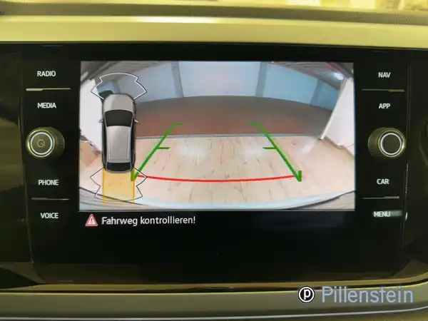 Innenaufnahme des Fahrzeugs zeigt das Navigations- bzw. Rückfahrkamera-Display mit einem Bild des Fahrzeugs und Text "Fahrweg kontrollieren!".