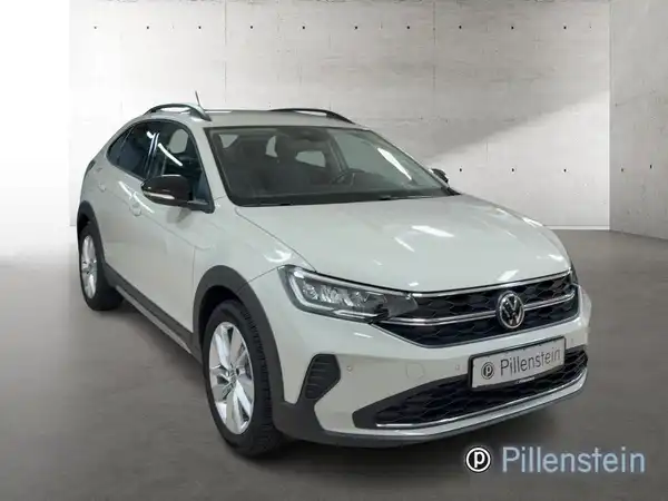 Das Bild zeigt einen weißen Volkswagen Taigo aus der Frontansicht. Das Händelermarkenzeichen ist sichtbar.