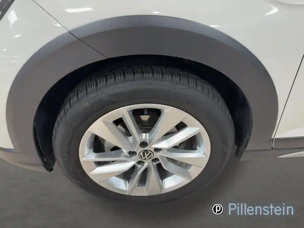 Das Bild zeigt ein seitliches Detail des VW Taigo mit einem weißen Farbschema, wobei der Wagenreifen und die Felge im Vordergrund stehen.