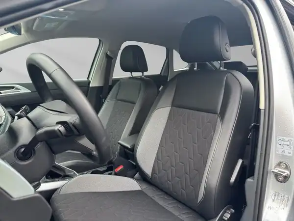 Das Bild zeigt den Innenraum eines silbernen VW Taigo aus einer Innenaufnahme. Die Sitze sind schwarz mit einem modernen Design.