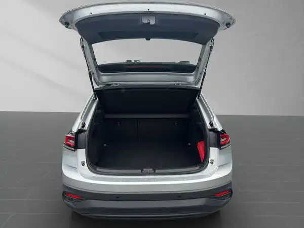 Das Bild zeigt den offenen Kofferraum eines silbernen VW Taigo von hinten.