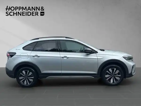 Das Bild zeigt einen silbernen VW Taigo aus der Seitenansicht. Oben links ist das Händlerlogo "HOPPMANN & SCHNEIDER" eingeblendet.