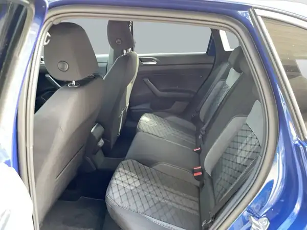 Das Bild zeigt den Innenraum eines VW TAIGO R-Line, aufgenommen von hinten. Die Sitze sind schwarz mit einem quilted Muster und das Fahrzeug ist blau.