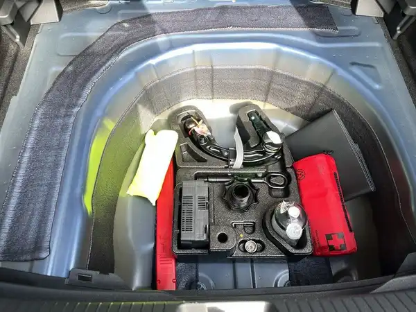 Das Bild zeigt den Kofferraum des Fahrzeugs mit verschiedenen Werkzeugen und Zubehörteilen.
