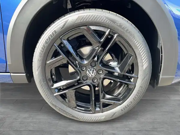 Das Bild zeigt das Rad eines blauen VW TAIGO R-Line von der Seite, mit sportlichem Design und schwarzen Felgen.