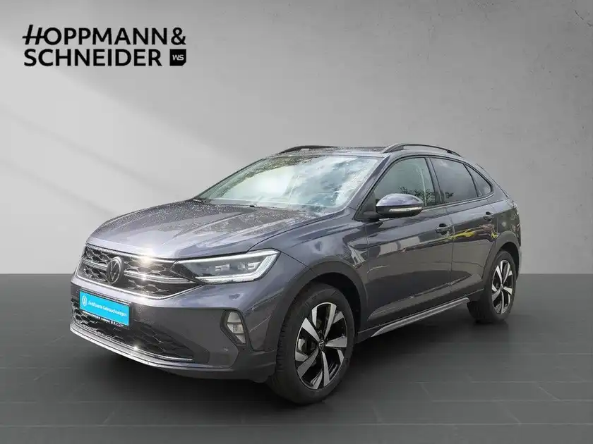 Das Bild zeigt einen grauen VW TAIGO STYLE von der Seite mit dem Händlerlogo "HOPPMANN & SCHNEIDER".