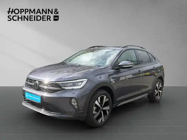 Das Bild zeigt einen grauen VW TAIGO STYLE von der Seite mit dem Händlerlogo "HOPPMANN & SCHNEIDER".