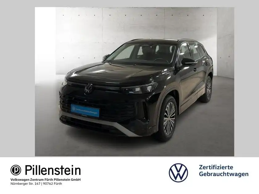 Das Bild zeigt einen schwarzen VW Tayron von vorne. Ein Händlerlogo ist eingeblendet.