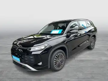 Das Bild zeigt einen VW TAYRON in schwarzer Farbe, aufgenommen von der Seite. Es sind markante Texteinblendungen auf dem Foto zu sehen.