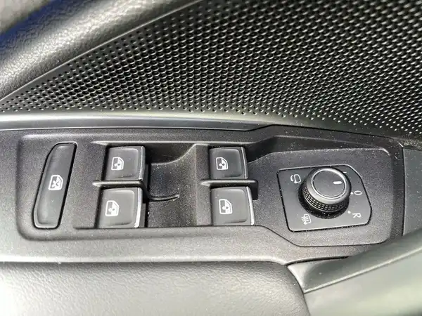 Das Bild zeigt eine Innenaufnahme des Fahrzeugs mit einem Knopf, vermutlich für die Motorhaube, auf einem schwarzen Armaturenbrett.