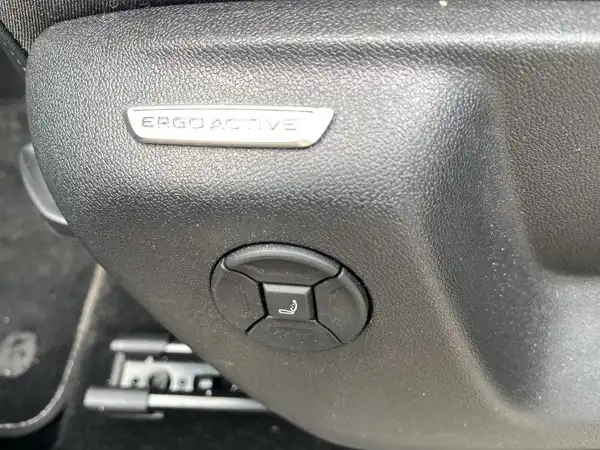 Das Bild zeigt eine seitliche Ansicht des Fahrzeugs in blauer Farbe, mit dem R-Logo am Türbereich. Es ist auf einer nassen Oberfläche aufgenommen.