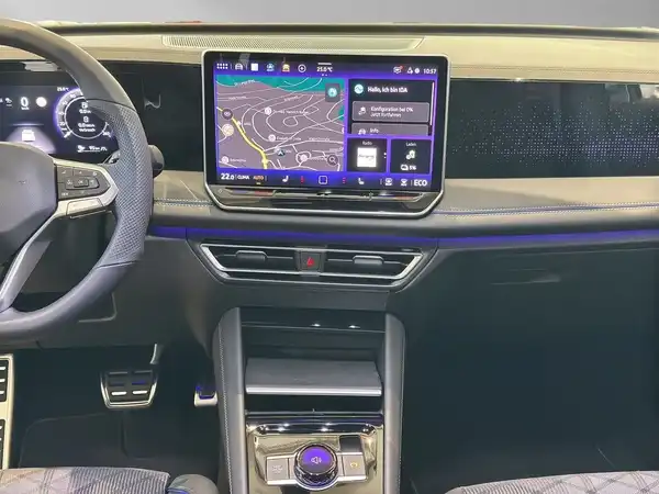 Innenaufnahme eines VW Tiguan mit dunklem Interieur und modernem digitales Cockpit, zeigt Kartenansicht und Texteinblendungen.