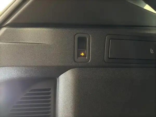Das Bild zeigt eine Innenaufnahme des VW Tiguan mit einem schwarzen Interieur. Es ist ein Schalter oder eine Anzeige auf dem Armaturenbrett zu sehen.