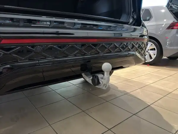 Das Bild zeigt die Rückansicht eines schwarzen VW Tiguan mit Anhängerkupplung, aufgenommen im Innenraum eines Autohauses.