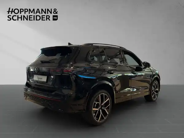 Das Bild zeigt einen schwarzen VW Tiguan aus der Rückansicht. Es ist ein Fahrzeugbild mit dem Logo des Händlers 'HOPPMANN & SCHNEIDER' im oberen Bereich.