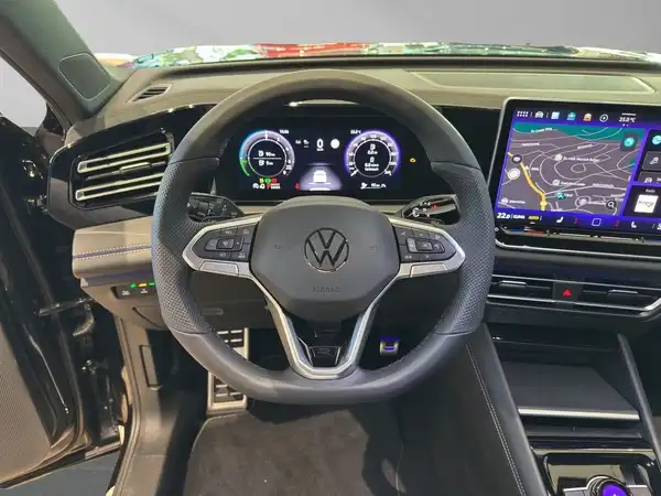 Das Bild zeigt das Innere eines VW Tiguan mit einem schwarzen Interieur und einem Blick auf das Lenkrad und das Armaturenbrett.