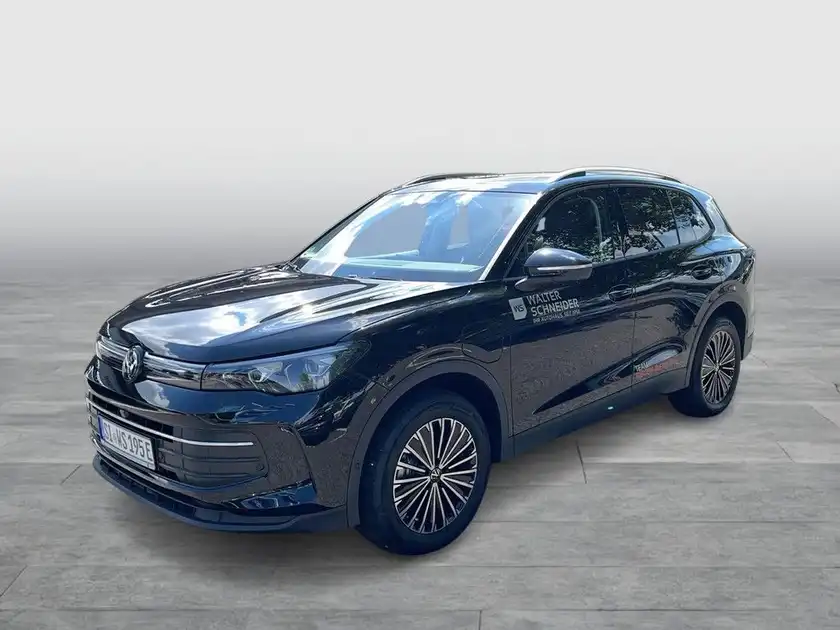 Das Bild zeigt einen schwarzen VW Tiguan von der Seite. Es enthält ein Händlerlogo und weist markante Texteinblendungen auf.