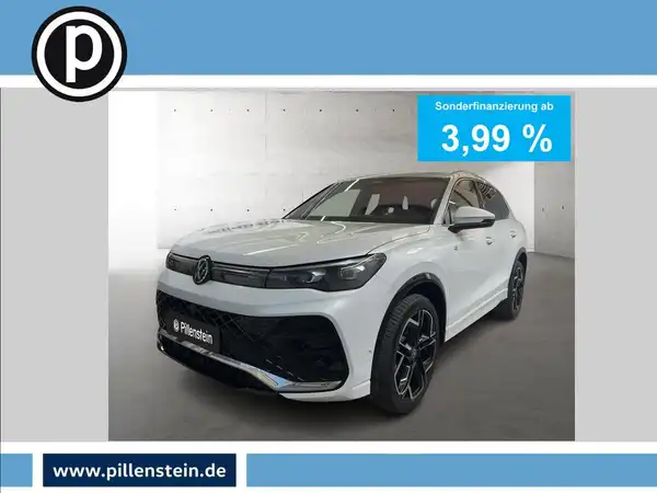 Das Bild zeigt einen weißen VW Tiguan aus der Frontalansicht mit einem Händlerlogo und einer Anzeige für Sonderfinanzierung.