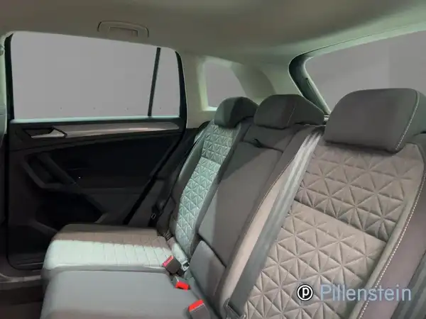 Das Bild zeigt den innenraum eines VW Tiguan aus der Sicht der Rückbank. Die Polster sind grau mit einem modernen Design.