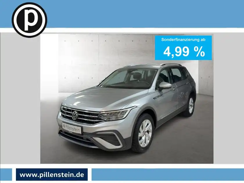 Das Bild zeigt einen silbernen VW Tiguan Allspace von vorne. Es enthält markante Texteinblendungen für eine Sonderfinanzierung und ein Händlerlogo.