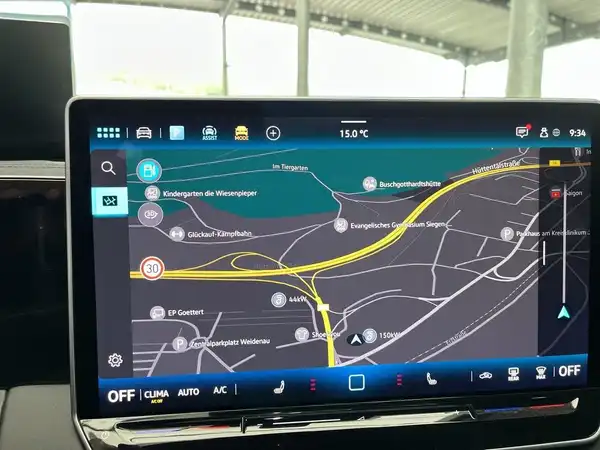 Das Bild zeigt das Innenleben eines VW Tiguan mit einem Bildschirm, der eine Rückfahrkamera darstellt. Zu sehen sind gelbe Linien, die den Parkierbereich anzeigen.