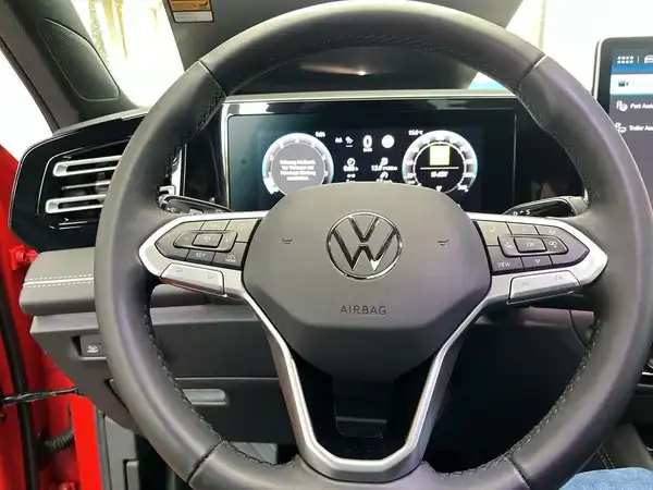 Aufnahme des Fahrzeuginnenraums eines VW Tiguan, Blick auf das Lenkrad und das Armaturenbrett in roter Innenausstattung.