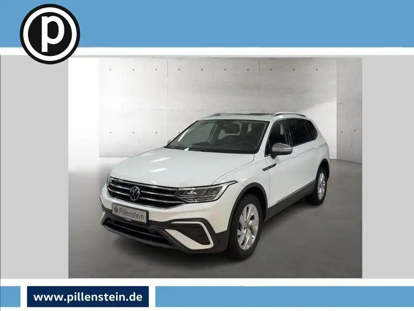 Das Bild zeigt einen weißen VW Tiguan Allspace von vorne. Das Händlerinformationen sind sichtbar.
