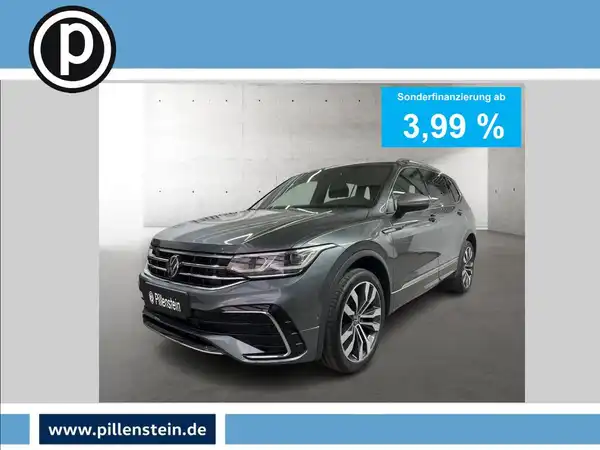 Das Bild zeigt einen VW Tiguan Allspace in grauer Farbe aus seitlicher Perspektive. Es enthält eine Anzeige für Sonderfinanzierung mit einem Zinssatz von 3,99 % sowie das Logo des Händlers.