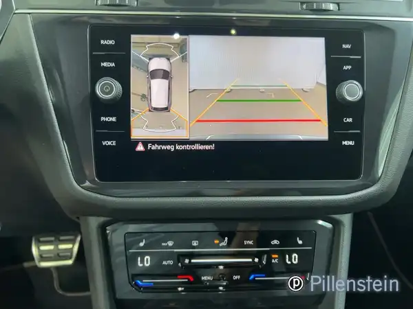 Innenaufnahme des Fahrzeugs mit einem Navigations-/Bildschirmdisplay, das Informationen zur Fahrt und zur Parkplatzbelegung zeigt.