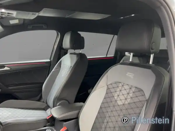 Das Bild zeigt den Innenraum eines VW Tiguan Allspace von einer Innenaufnahme mit schwarzen, gemusterten Sitzen.