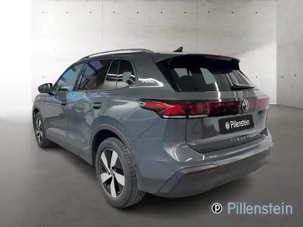 Das Bild zeigt einen VW Tiguan von hinten. Das Fahrzeug ist grün und vor einem neutralen Hintergrund abgebildet. Es gibt keine markanten Texteinblendungen außer dem Händlerlogo.