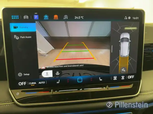 Das Bild zeigt den Innenraum eines VW Tiguan mit angezeigtem Parkassistenten auf dem Bildschirm. Der Interieur ist schwarz und es sind markante Texteinblendungen zu sehen.