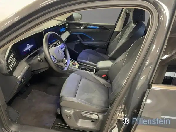 Das Bild zeigt den Innenraum eines VW Tiguan aus einem Blickwinkel von der Seite, in Schwarz mit grauen und schwarzen Akzenten, einschließlich Händlerinformationen.