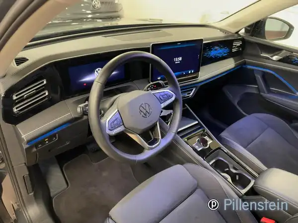 Das Bild zeigt das Innenraum eines VW Tiguan in schwarz mit blauen Akzenten. Es gibt ein Händlerlogo im Bild.